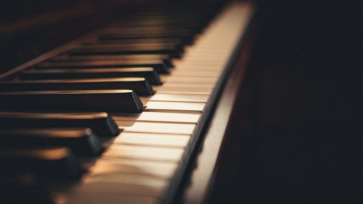Close-up of warm-lit piano keys with one black key pressed, illustrating the single chromatic note a secondary dominant adds from outside the key